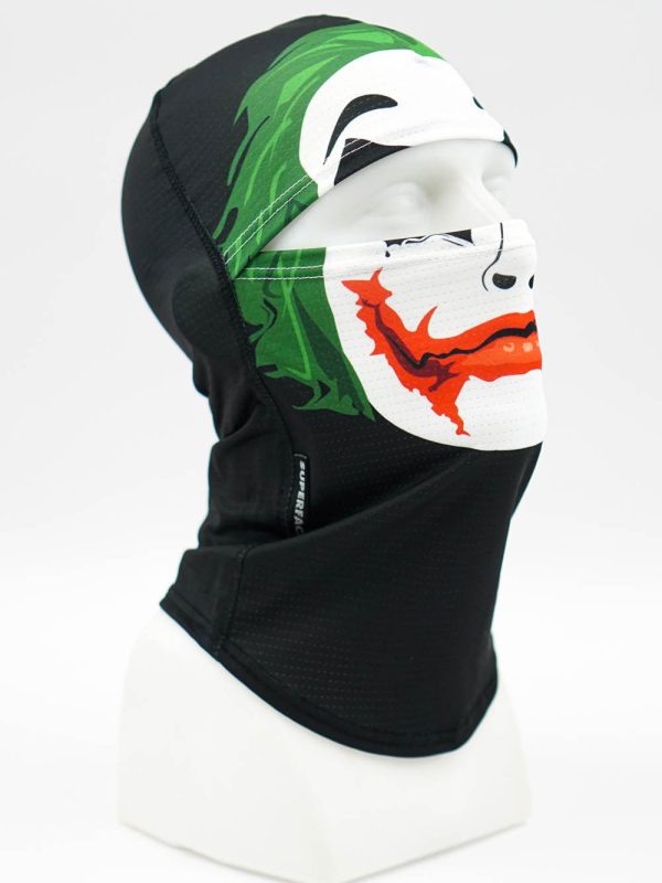 Black balaclava/neck gaiter on a mannequin head with a colorful graphic mask featuring green hair and a red mouth design on white.