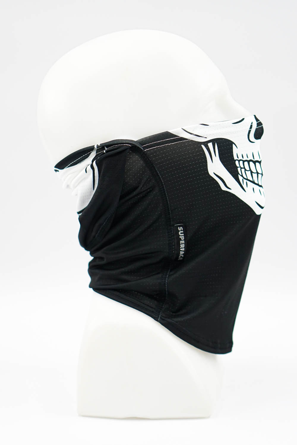 Black fabric neck gaiter with a white skull graphic draped around a white mannequin head, side view showing tag.